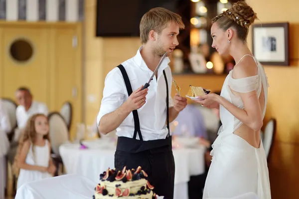 Šťastné nevěsty a ženicha, snížení jejich svatební dort — Stock fotografie