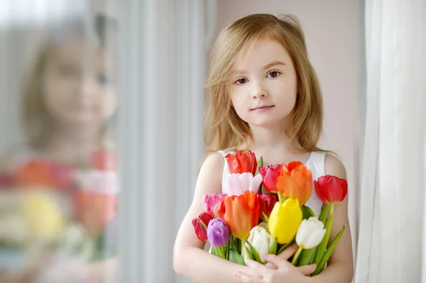Adorable petite fille avec des tulipes près de la fenêtre — Photo