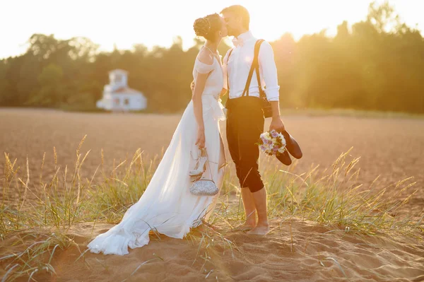 Novia y novio en una playa al atardecer —  Fotos de Stock