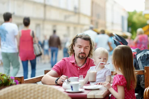 Отец и его дочери отдыхают в кафе на открытом воздухе — стоковое фото