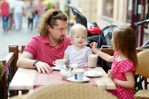 Отец и его дочери отдыхают в кафе на открытом воздухе — стоковое фото