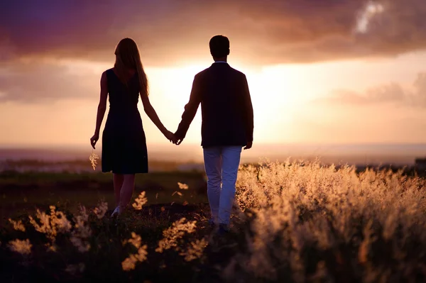 Pareja joven disfrutando de la puesta de sol — Foto de Stock