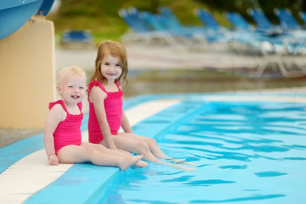 Sisters sitting by a swimming pool — Stock Photo, Image