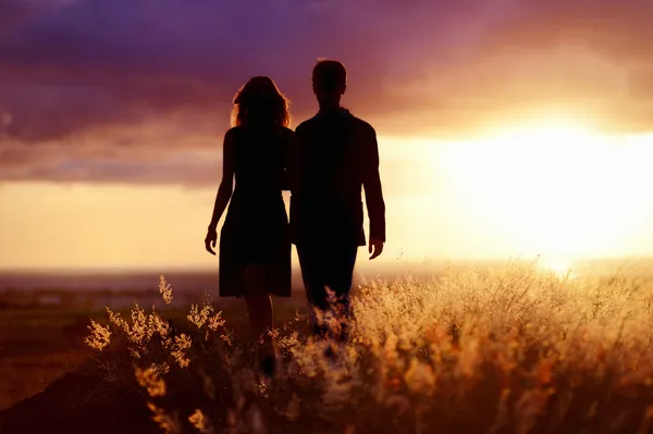 Pareja joven disfrutando de la puesta de sol — Foto de Stock