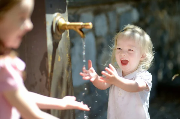 Zwei Mädchen mit Wasserfontäne — Stockfoto