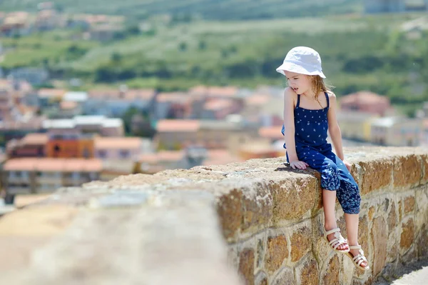 Liten flicka sitter på väggen — Stockfoto