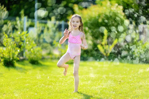 Girl running though   sprinkler — Stock Photo, Image