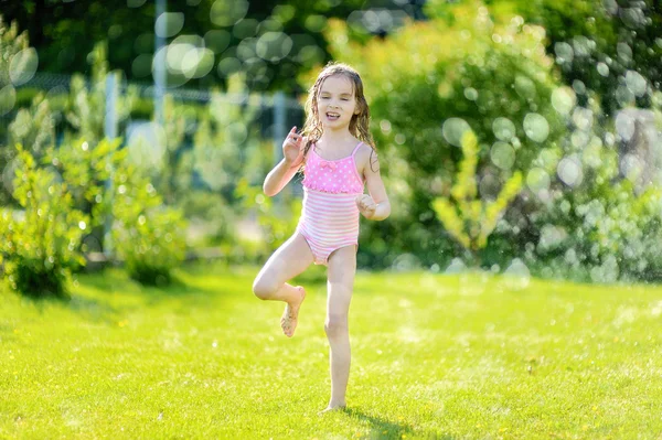 Meisje uitgevoerd hoewel sprinkler — Stockfoto