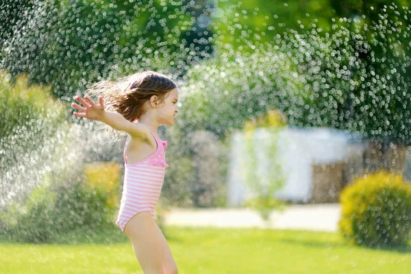 Girl running though  sprinkler — Stock Photo, Image