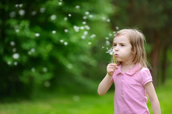 小さな女の子吹くタンポポ — ストック写真