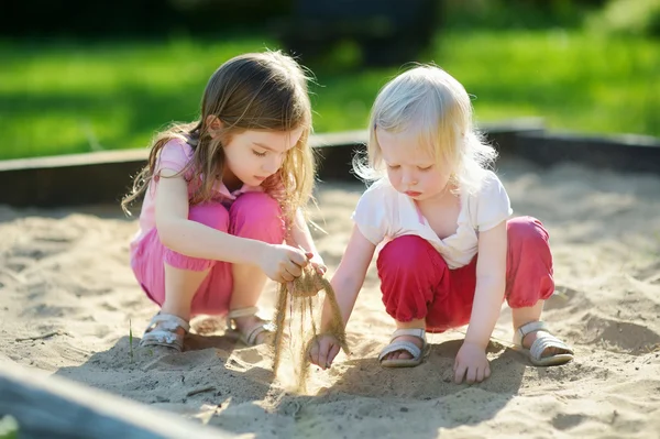 Маленькие сестры в песочнице — стоковое фото
