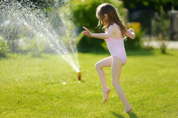 Girl running though   sprinkler — Stock Photo, Image