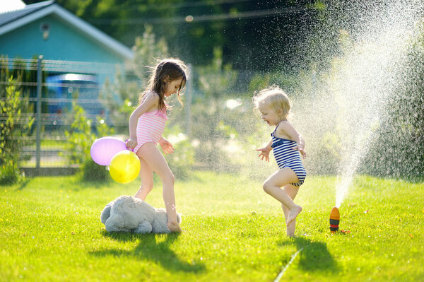 Girls running though   sprinkler