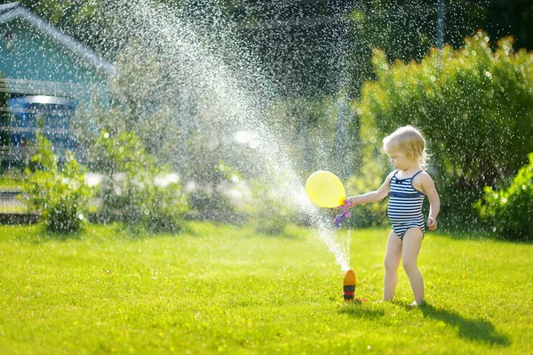 Girl running though  sprinkler — Stock Photo, Image