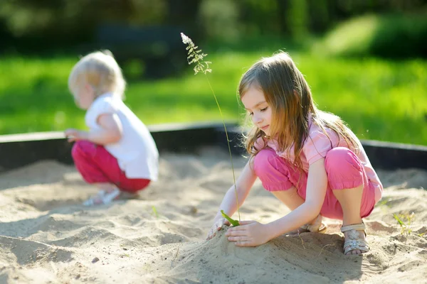 Zwei kleine Schwestern im Sandkasten — Stockfoto