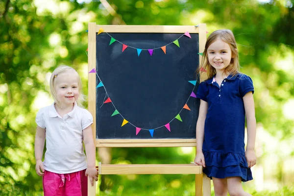 Kleine zusters door schoolbord — Stockfoto