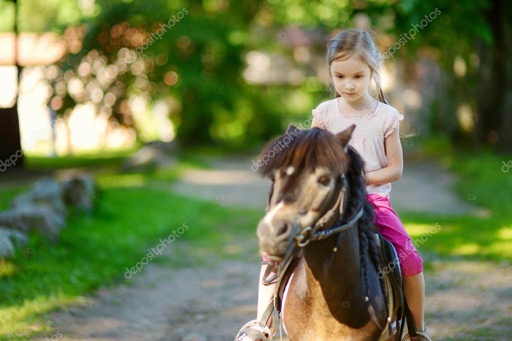 Little girl riding pony Stock Photo by ©MNStudio 49276085