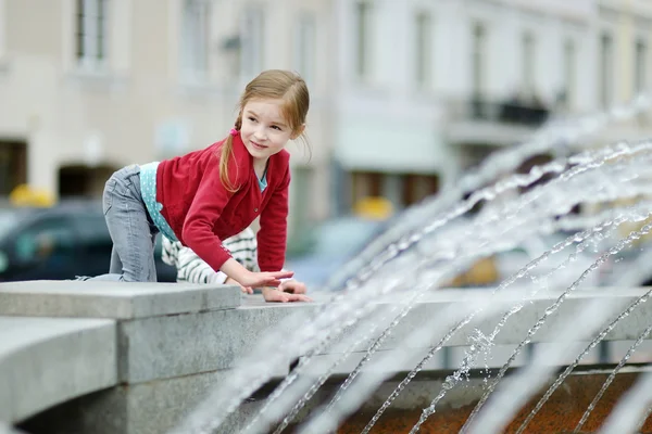 Malá dívka si hraje s fontánou — Stock fotografie