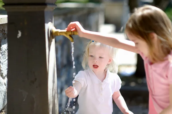 Sœurs jouant avec fontaine — Photo