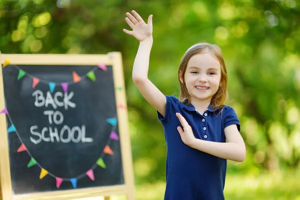 Weinig schoolmeisje door schoolbord — Stockfoto