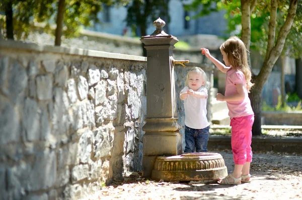 Sisters playing at fountain — Stock Photo, Image