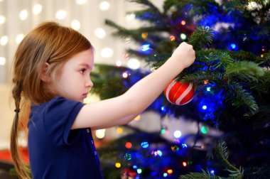 Noel ağacı süsleyen küçük kız