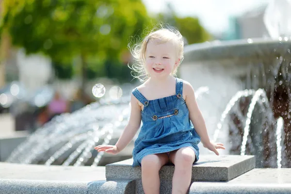 Leuk meisje spelen met fontein — Stockfoto