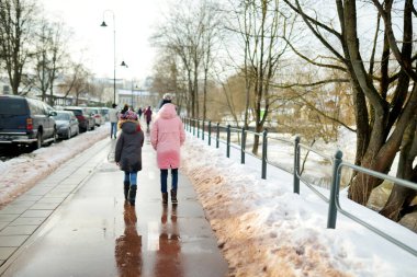 İki sevimli genç kız kardeş güzel bir kış gününde şehirde eğleniyorlar. Kış kasabasında yürüyüş yapan sevimli çocuklar. Çocuklar için kış aktiviteleri.