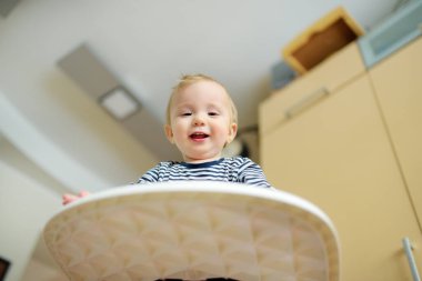Beyaz bir sandalyede oturan tatlı bir erkek bebek. İlk katı besinleri tanıtıyorum. Bebekler için taze organik sebzeler. Çocuklu aileler için sağlıklı beslenme.