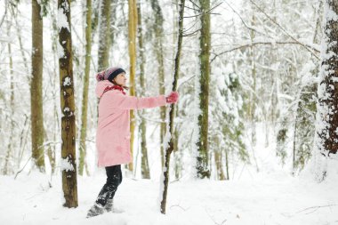 Tatlı genç kız kar yağarken güzel kış parkında eğleniyor. Karda oynayan sevimli bir çocuk. Çocuklu aileler için kış etkinlikleri.