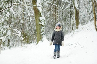 Tatlı genç kız kar yağarken güzel kış parkında eğleniyor. Karda oynayan sevimli bir çocuk. Çocuklu aileler için kış etkinlikleri.
