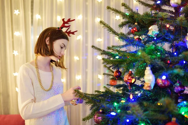 可爱的小女孩用彩色玻璃幕布装饰圣诞树 修剪圣诞树的时候在家里庆祝圣诞节 — 图库照片