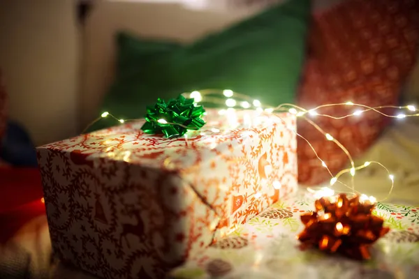 Завернутые Рождественские Подарочные Коробки Украшенные Бантиками Сидящими Диване Рождественские Огни — стоковое фото