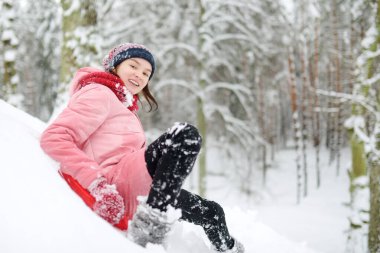 Tatlı genç kız kar yağarken güzel kış parkında eğleniyor. Karda oynayan sevimli bir çocuk. Çocuklu aileler için kış etkinlikleri.
