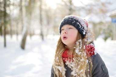 Tatlı genç kız kar yağarken güzel kış parkında eğleniyor. Karda oynayan sevimli bir çocuk. Çocuklu aileler için kış etkinlikleri.