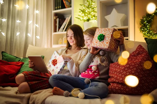 クリスマスの暖かく居心地の良いリビングルームで自宅でタブレットPcを使用して2人のかわいい妹 Xmas Eveでオンラインビデオ通話を持つ家族 家族や子供と家で冬の夜 — ストック写真