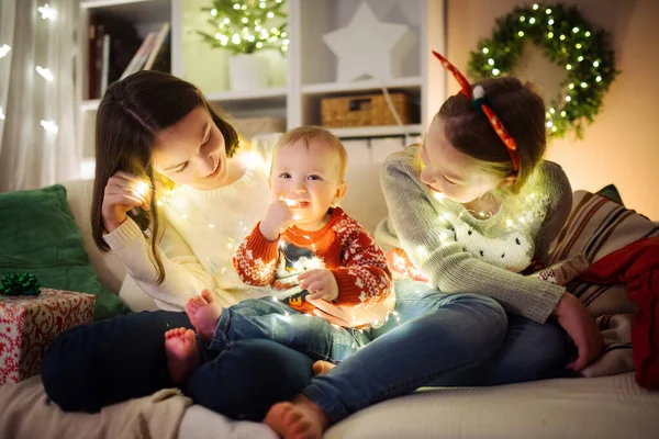 2人の姉とかわいい弟はクリスマスの前夜に居心地の良いリビングルームで一緒に楽しんでいます 子供たちは冬休みに家で時間を過ごす 家族や子供と冬の夜 — ストック写真