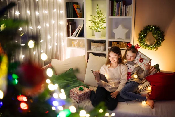 Noel Evde Sıcak Rahat Oturma Odasında Tablet Kullanan Iki Kız — Stok fotoğraf