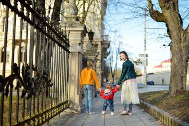 Küçük erkek kardeşle sokakta kız kardeşlerin arka görüntüsü.