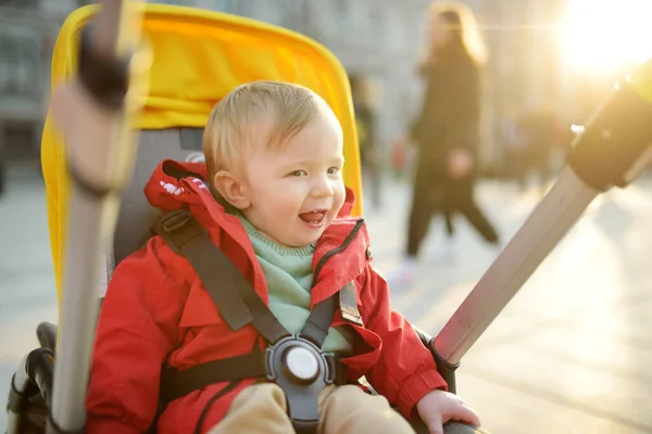 屋外のベビーカーに座っている赤いジャケットを着た甘い赤ちゃん 祈りの中の小さな子供 幼児はプッシュチェアで 春は子供たちと歩く 小さな子供と家族のレジャー — ストック写真