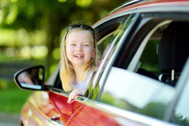 Kafasını arabanın camından çıkaran komik genç bir kız yolculuk ya da yolculuk için sabırsızlanıyor. Çocuklarla aile gezisi..