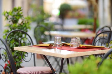 Montalcino kasabasının ortaçağ caddesinde boş bir restoran masası tepenin üstünde ve dünya çapında lezzetli şarap üretimiyle bilinen üzüm bağlarıyla çevrili. Toskana, İtalya.