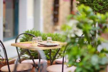 Montalcino kasabasının ortaçağ caddesinde boş bir restoran masası tepenin üstünde ve dünya çapında lezzetli şarap üretimiyle bilinen üzüm bağlarıyla çevrili. Toskana, İtalya.