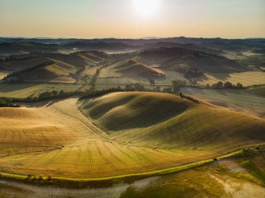 Ufukta küçük köyleri olan tarlaları ve tarlaları sabah görüşü göz kamaştırıcı. İtalya, Toskana 'nın kayan tepeleri, kıvrımlı yolları ve selvilerinin yaz manzarası.