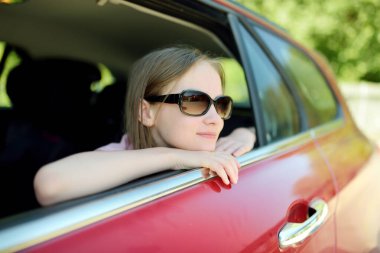 Kafasını arabanın camından çıkaran komik genç bir kız yolculuk ya da yolculuk için sabırsızlanıyor. Çocuklarla aile gezisi..