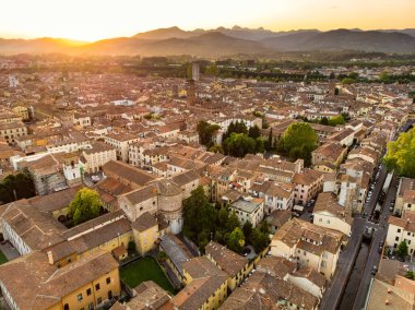 El değmemiş Rönesans dönemi şehir duvarları ve iyi korunmuş tarihi merkeziyle ünlü Lucca şehrinin hava günbatımı manzarası. Lucca ili, Toskana, İtalya.