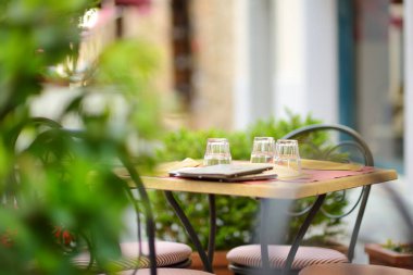 Montalcino kasabasının ortaçağ caddesinde boş bir restoran masası tepenin üstünde ve dünya çapında lezzetli şarap üretimiyle bilinen üzüm bağlarıyla çevrili. Toskana, İtalya.