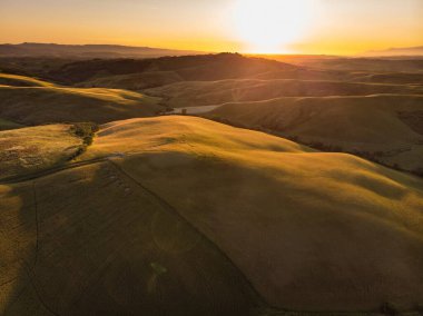 Ufukta küçük köyleri olan tarlaları ve tarlaları sabah görüşü göz kamaştırıcı. İtalya, Toskana 'nın kayan tepeleri, kıvrımlı yolları ve selvilerinin yaz manzarası.