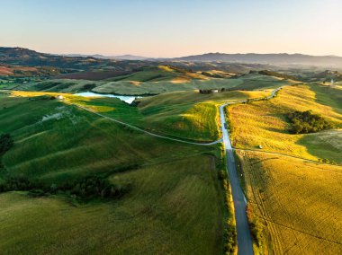 Ufukta küçük köyleri olan tarlaları ve tarlaları sabah görüşü göz kamaştırıcı. İtalya, Toskana 'nın kayan tepeleri, kıvrımlı yolları ve selvilerinin yaz manzarası.