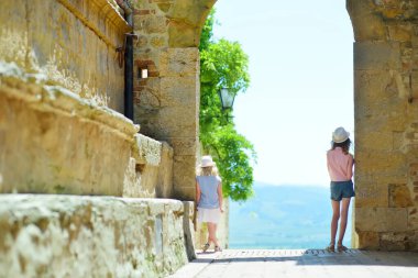 Ufukta küçük köyleri olan yeşil tarlalara ve tarım arazilerine hayran olan iki kız kardeş. İtalya, Toskana 'daki Pienza kasabasını çevreleyen yuvarlak tepelerin yaz manzarası.